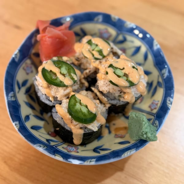Sushi rolls topped with spicy sauce and jalapeños, served with pickled ginger and wasabi.