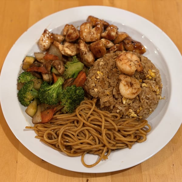 Hibachi chicken, shrimp, fried rice, noodles, and mixed vegetables on a white plate.