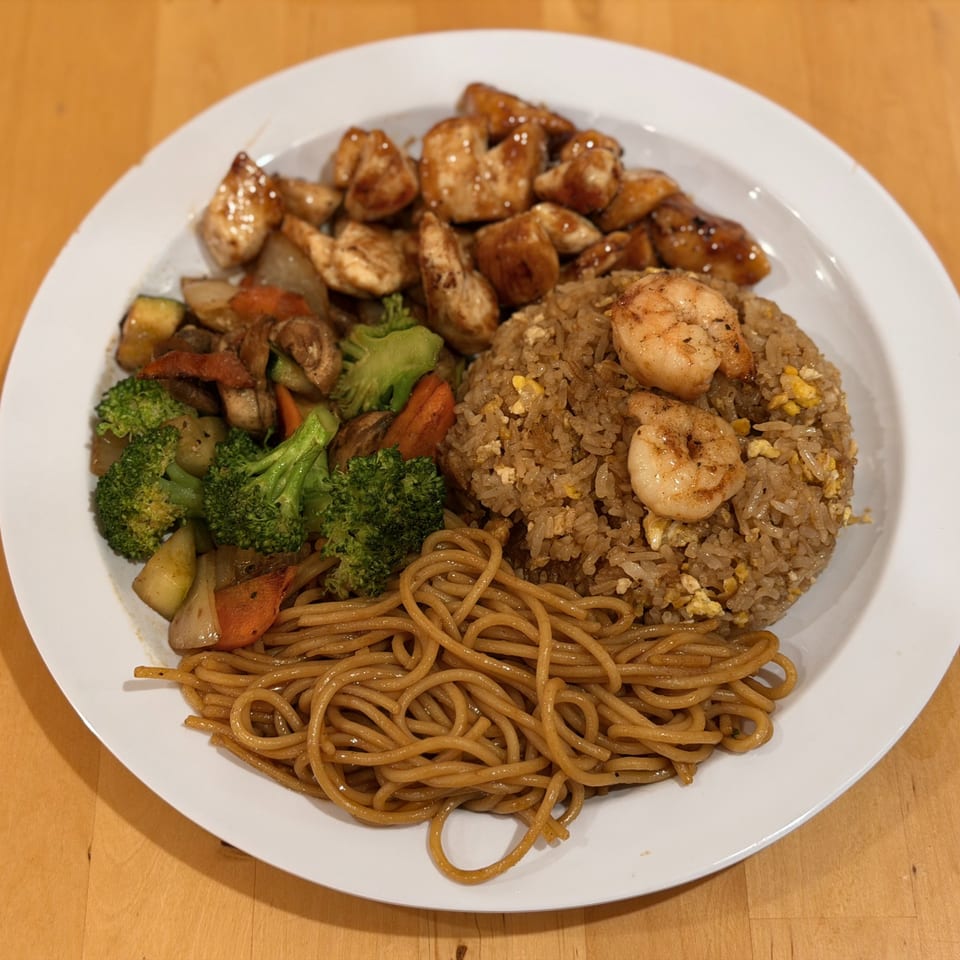 Hibachi chicken, shrimp, fried rice, noodles, and mixed vegetables on a white plate.